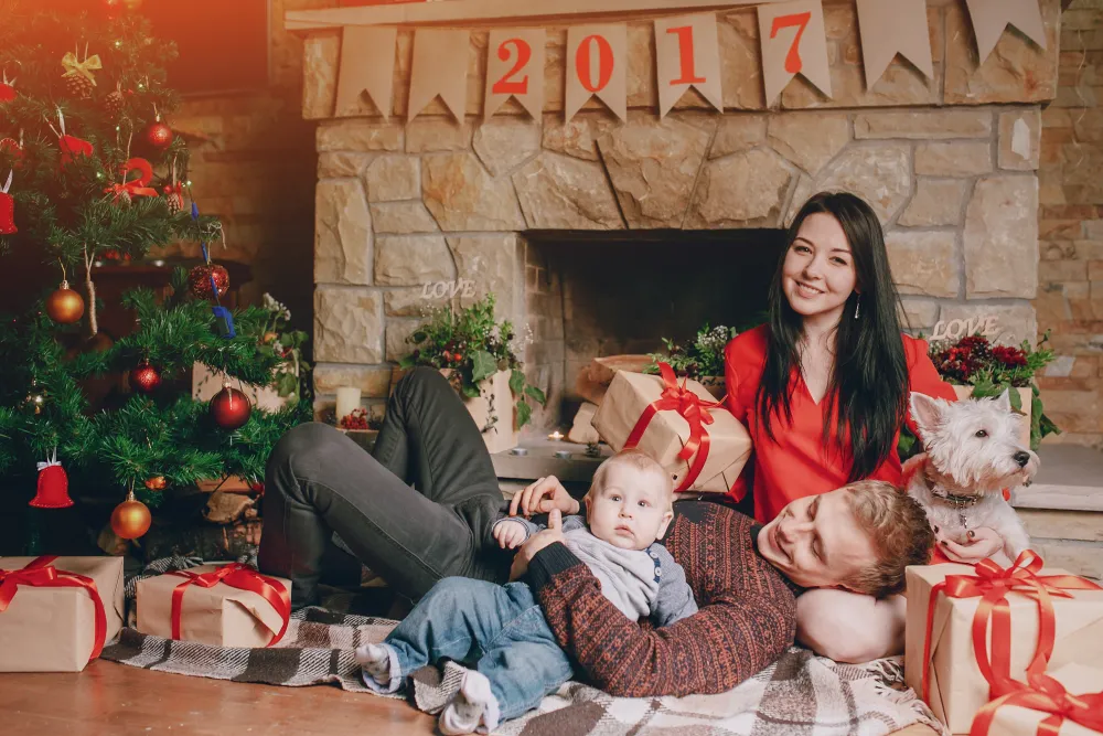 Familie sitzt mit verpackten Geschenken vor dem Weihnachtsbaum