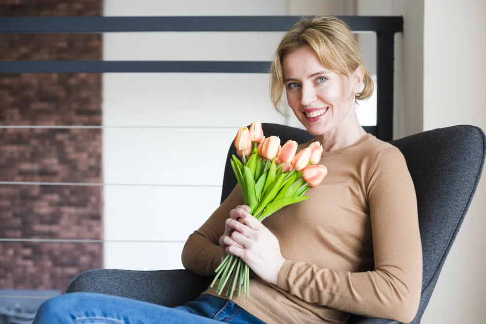 Frau sitzt mit einem Tulpenstrauß im Sessel